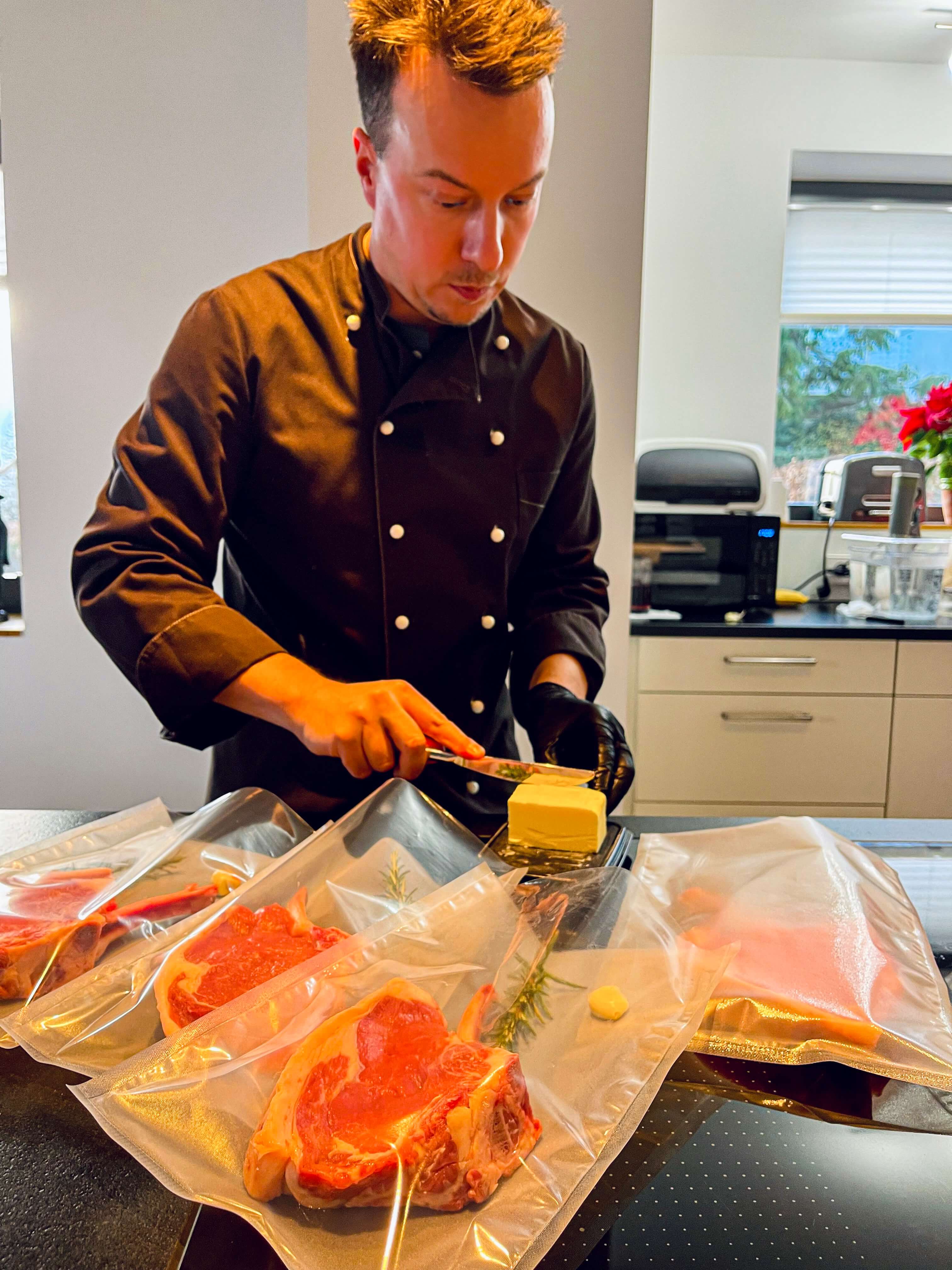 Me in a chef's vest filling several sous vide bags